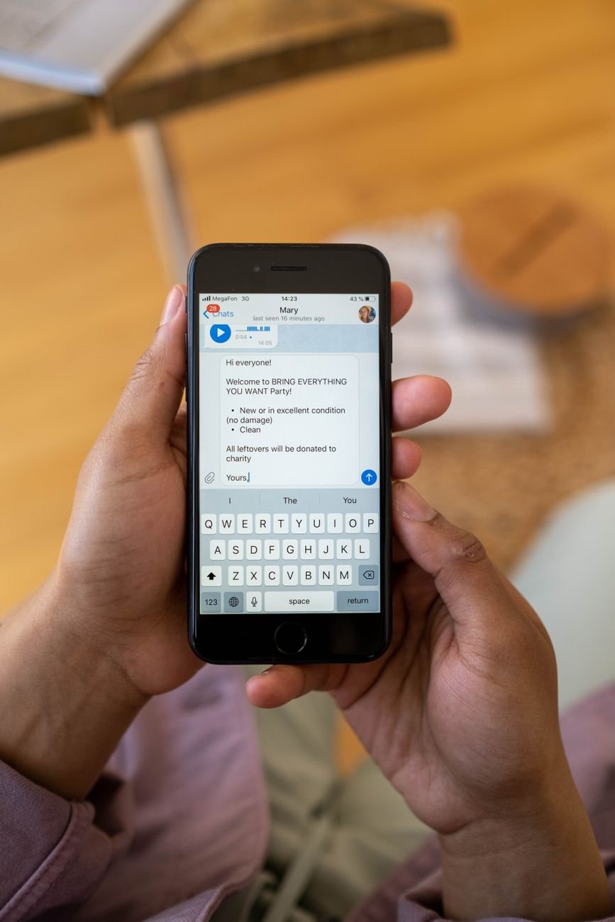 Close-up of hands holding a smartphone while typing a text message indoors.